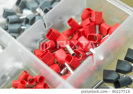 A set of red crimp terminals for electrical wires. Crimping sleeves of different sizes. Plastic spare parts box for electrician. Toolbox. Selective focus 90227518