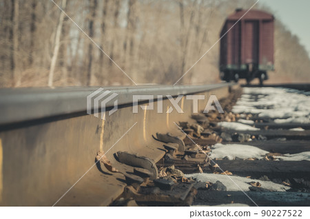 Close-up of old railway nails to attach rails to wooden sleepers. Blurred freight wagon stands on the spare track of the railway. Selective focus 90227522