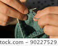 Close-up hand knitting. Hobbies, handicrafts. Knitting warm clothes from woolen fine yarn by hand on metal needles. Selective focus 90227529