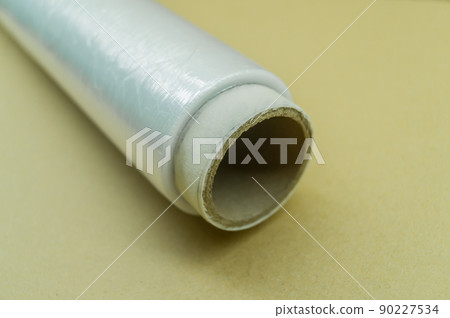 Roll of food stretch film for food packaging. Packaging film in a roll on a cardboard spool. Selective focus Roll of food stretch film for food packaging. Packaging film in a roll on a cardboard spool. Selective focus 90227534
