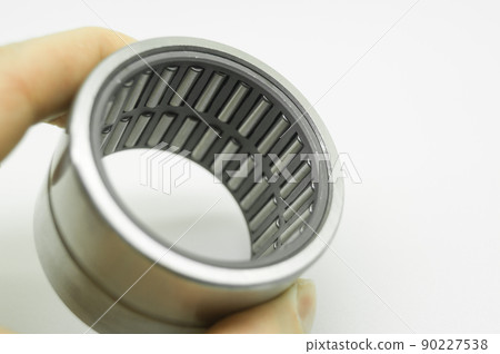 Needle bearing in hand. Roller bearing for motors, machinery and equipment. Spare part. Selective focus, isolated on white Needle bearing in hand. Roller bearing for motors, machinery and equipment. Spare part. Selective focus, isolated on white 90227538