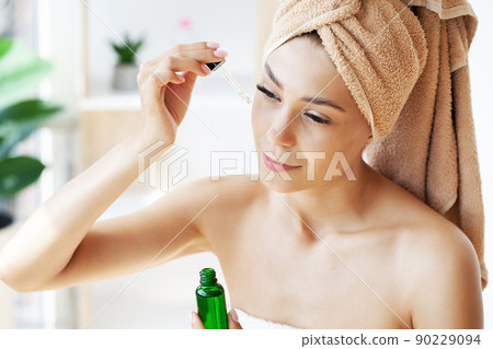 Beauty portrait of smiling young woman girl holding pipette with cosmetic oil or serum near clean face. 90229094