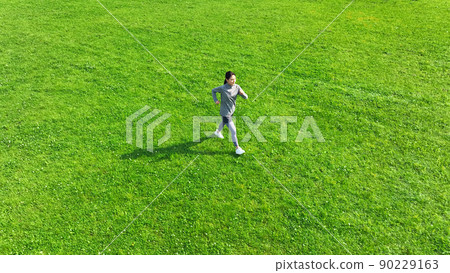 Aerial view of a woman running in the meadow Aerial view of a woman running in the meadow 90229163
