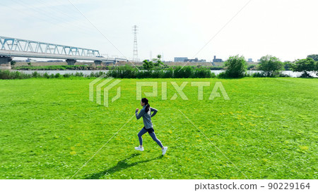 Aerial view of a woman running in the meadow Running 90229164