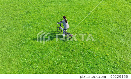 A woman riding a bicycle through the meadow A woman riding a bicycle through the meadow 90229166