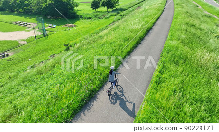 A woman riding a bicycle on the bank 90229171