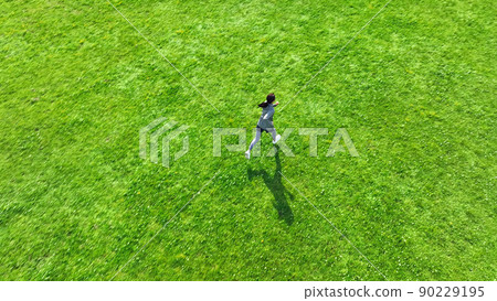 Aerial view of a woman running in the meadow Aerial view of a woman running in the meadow 90229195