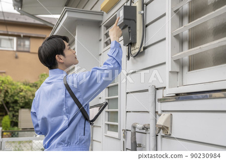 一個穿著工作服的男人在房子裡檢查電錶 90230984