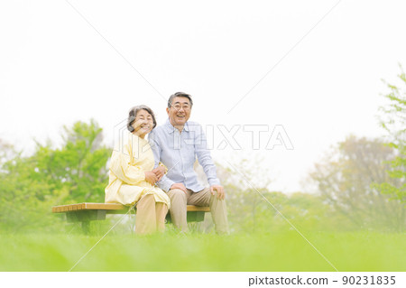 Senior couple sitting on a bench early summer Senior couple sitting on a bench early summer 90231835