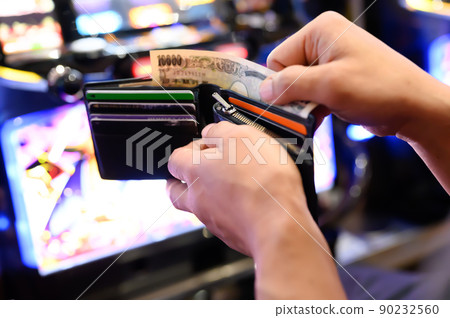 Investing a 10,000 yen bill from a wallet at a pachinko parlor 90232560