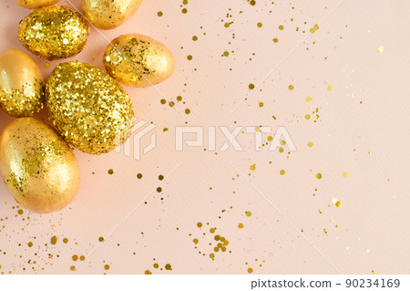 Easter eggs with gold sequins on a beige background. 90234169