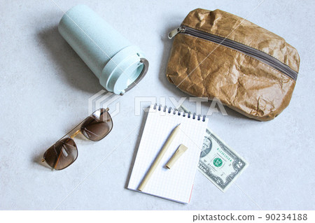 Pen, bag, cardboard cup made of recycled paper. Travel composition with sunglasses and dollars. Eco friendly modern objects from ecological biomaterials. 90234188