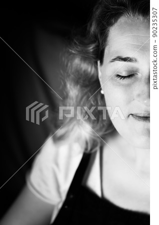 Black and white photo of a woman. A large portrait on a dark background. Vertical photo. 90235307