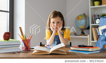 Thinking child is sitting at desk 90235620