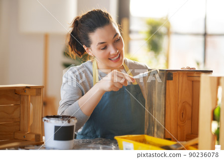woman is painting a wooden crate 90236078