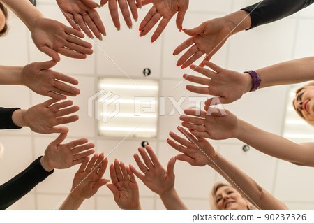 Team of people holding hands. Group of happy young women holding hands. Bottom view, low angle shot of human hands. Friendship and unity concept 90237326