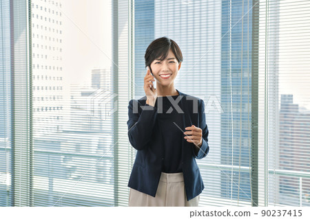Business woman looking at a smartphone in the office 90237415