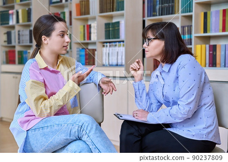 Psychologist, high school behavior counseling teenage student in library Psychologist, high school behavior counseling teenage student in library 90237809
