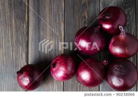 Lots of red onions on a brown wooden background. Red onions on old crumpled burlap. Copy space Lots of red onions on a brown wooden background. Red onions on old crumpled burlap. Copy space 90238066