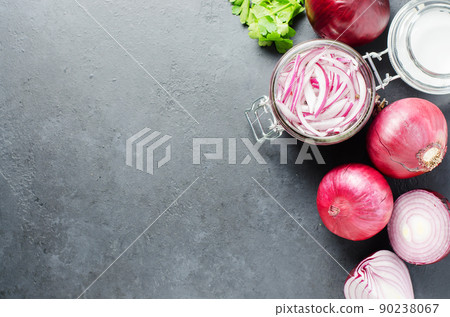 Pickled chopped red onion in vinegar in a glass jar. A delicious side dish for meat and fish dishes. Light grey background. 90238067