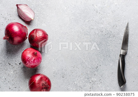 Lots of red onions on a gray concrete background. Flat top view Lots of red onions on a gray concrete background. Flat top view 90238075