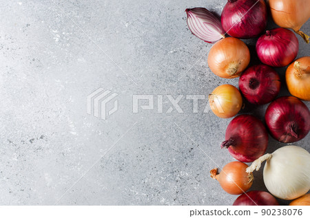 Lots of red onions on a gray concrete background. Flat top view Lots of red onions on a gray concrete background. Flat top view 90238076