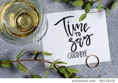 Time to say goodbye. The inscription on a white paper sheet. White wine in a glass glass. Gold engagement ring. Concept - deterioration of relations between people 90238426
