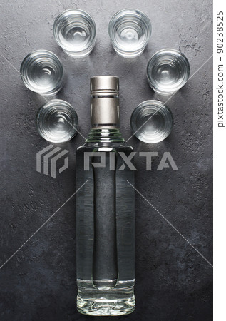 A bottle of vodka and six glasses on a dark background. Flat Lay 90238525