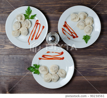 Traditional Russian dumplings, ravioli, dumplings on a white plate with red sauce and parsley. Dark wooden background. Traditional Russian dumplings, ravioli, dumplings on a white plate with red sauce and parsley. Dark wooden background. 90238561