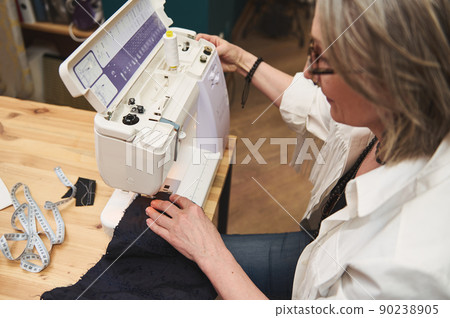 Close-up of a female tailor sewing clothes on sewing machine in tailoring atelier. Creation of new garment, fashion designer business start-up concept 90238905