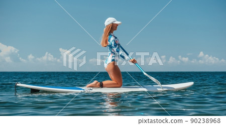 Healthy happy fit woman in bikini relaxing on a sup surfboard, floating on the clear turquoise sea water. Recreational Sports. Stand Up Paddle boarding. Summer fun, holidays travel. Active lifestyle 90238968