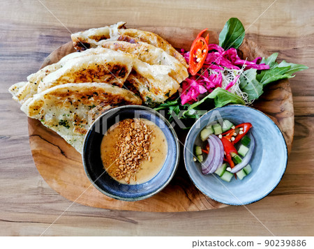 Garlic naan roti lightly grilled flat bread with peanut satay sauce and garden salad and cucumber vinegar relish Garlic naan roti lightly grilled flat bread with peanut satay sauce and garden salad and cucumber vinegar relish 90239886