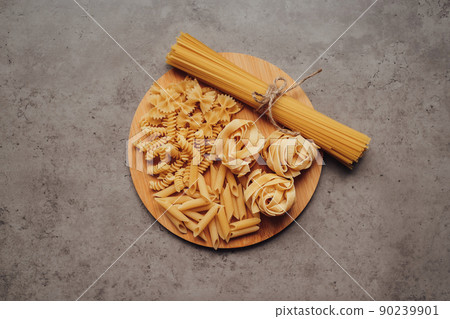Different Types of Pasta and Handful of Spaghetti on the Tray on the Background Table 90239901