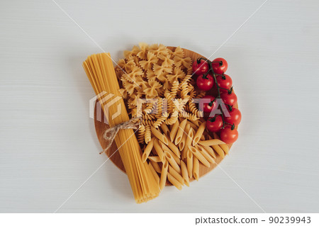 Different Types of Pasta and Cherry Tomatoes on the Tray on the White Background Table 90239943