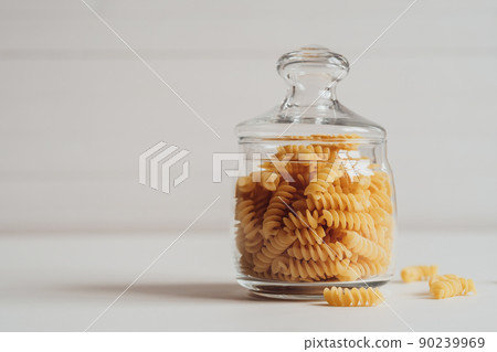 Pile of Wavy Pasta Stored in Glass on a White Background Pile of Wavy Pasta Stored in Glass on a White Background 90239969