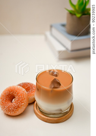 Iced latte, a glass of iced latte with tasty donuts on white office desk Iced latte, a glass of iced latte with tasty donuts on white office desk 90239985