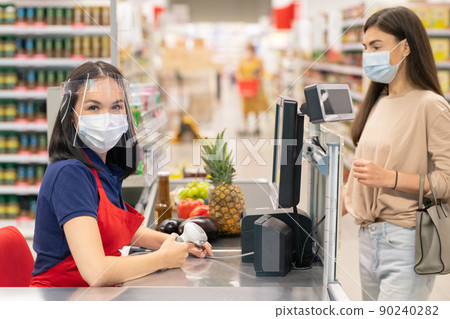 Modern store worker and customer following personal protection rules during Covid-19 quarantine days, wearing masks 90240282