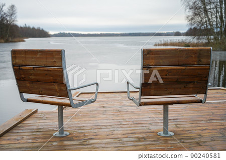 Metal with wooden cover modern chairs at the relaxation area in front of the lake Metal with wooden cover modern chairs at the relaxation area in front of the lake 90240581