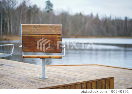 Metal with wooden cover modern chairs at the relaxation area in front of the lake Metal with wooden cover modern chairs at the relaxation area in front of the lake 90240591
