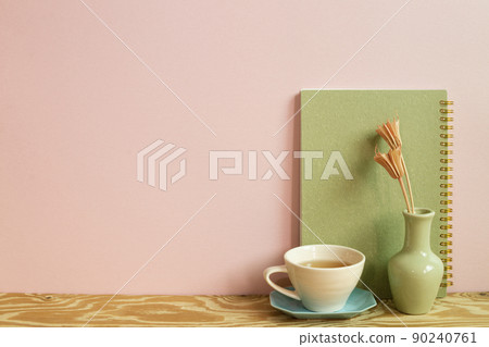 Notebook and cup of tea, dry flowers on wooden desk. pink wall background. workspace 90240761