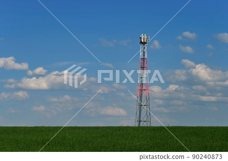 Telecommunication Tower - Transmitter for gsm signal of mobile phones in the field. In the background blue sky with clouds. Concept for modern technology and industry. 90240873