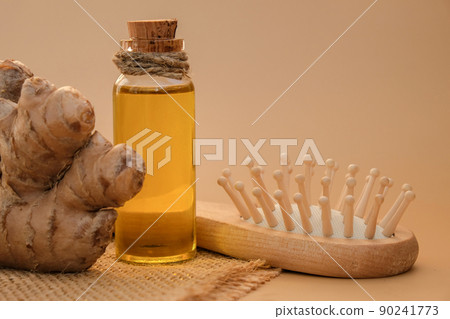 Glass bottle of essential ginger oil, ginger root on beige background. Healthy alternative living. Natural cosmetics ingredients for hair care. Wellness Eco comb Homemade hair mask treatment 90241773
