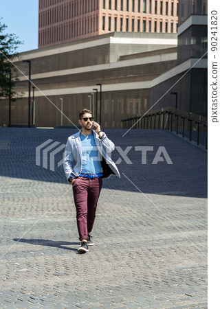 Young bearded man walking while talking by mobile phone 90241820