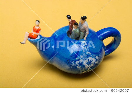 Group of miniature people figures standing in the teapot 90242007