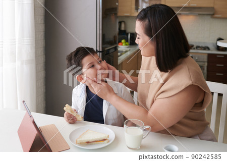 Mother squishing Chubby Cheeks of Son 90242585