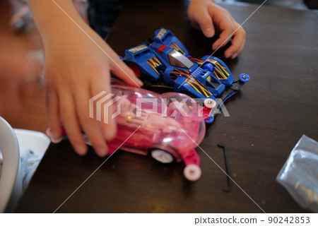 Hands of two kids with blue and pink car toys Hands of two kids with blue and pink car toys 90242853