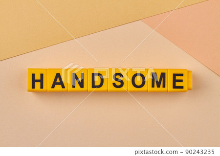 The word handsome written on yellow cubes on color background close up. The word handsome written on yellow cubes on color background close up. 90243235