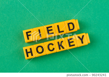 The inscription field hockey written on yellow cubes against green background. 90243241