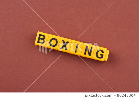 The word boxing written on yellow cubes against brown background. 90243304