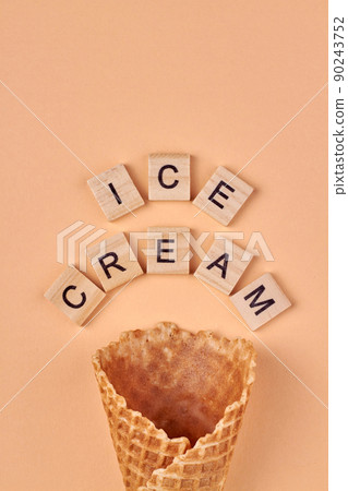 Flat lay composition with waffle cone and inscription ice cream on wooden cubes. 90243752